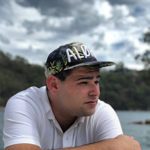 Andrew Joseph, founder of Afishonado, in a cap and white polo beside the water